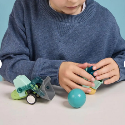 Criança com camisola azul a brincar com brinquedo desmontável e bola azul