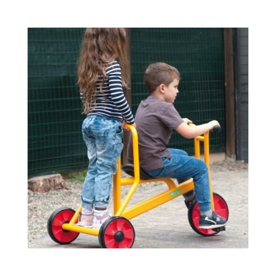 Crianças numa bicicleta amarela com rodas vermelhas num espaço exterior