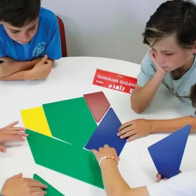 Crianças a montar tangram gigante colorido numa mesa branca