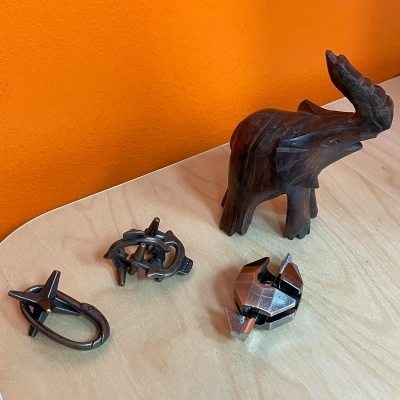 Objetos metálicos e elefante de madeira sobre mesa de madeira e parede laranja