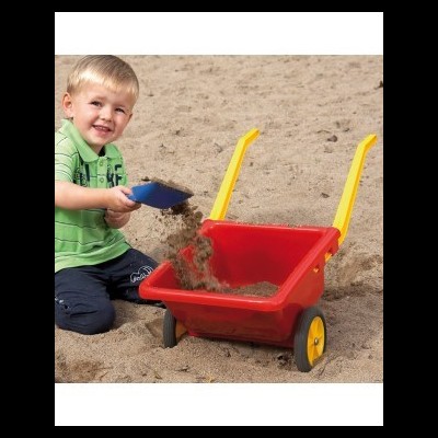 Criança com pá azul e carrinho vermelho a brincar na areia