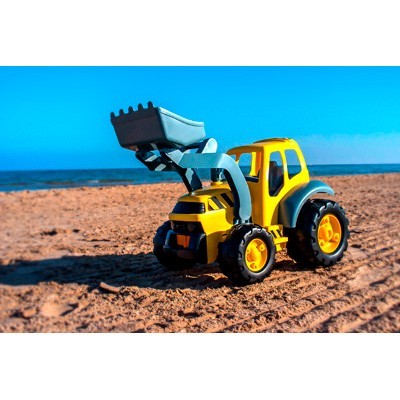 Brinquedo de camião amarelo com pá azul na areia da praia