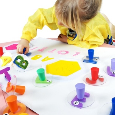 Criança a usar carimbos de letras coloridos em papel branco