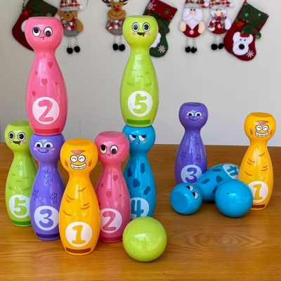 Jogo de boliche infantil colorido com pinos numerados e bolas em mesa de madeira com decoração de Natal ao fundo