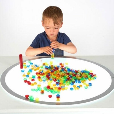 Criança a brincar com ímanes coloridos numa mesa branca circular