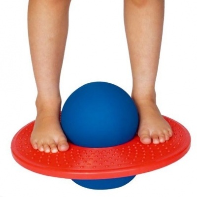 Prancha de equilíbrio azul e vermelha com pés descalços de criança