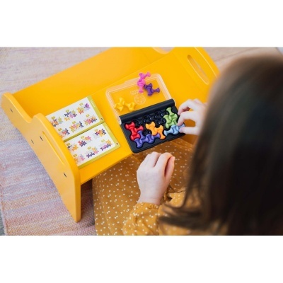 Jogo de raciocínio com peças coloridas e cartões sobre mesa amarela