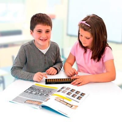 Duas crianças usando um ábaco numa mesa com um livro aberto