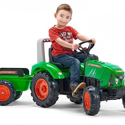 Criança num tractor infantil de brinquedo verde com reboque