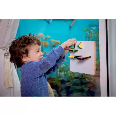 Criança brinca com brinquedo educativo colorido numa janela de vidro