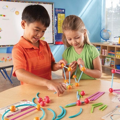 Crianças montam construções coloridas numa sala de aula