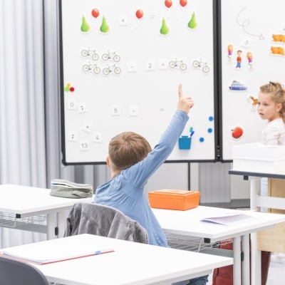 Crianças na sala de aula com quadros brancos decorados com ímanes coloridos, mesas e cadeiras