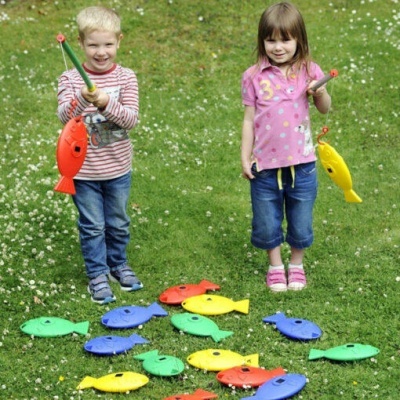 Crianças brincando com varas de pesca e peixes de brinquedo coloridos no relvado