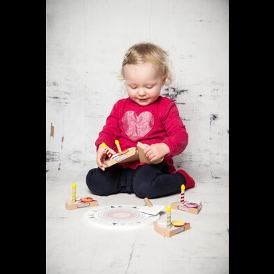 Criança sentada a brincar com brinquedo de madeira colorido