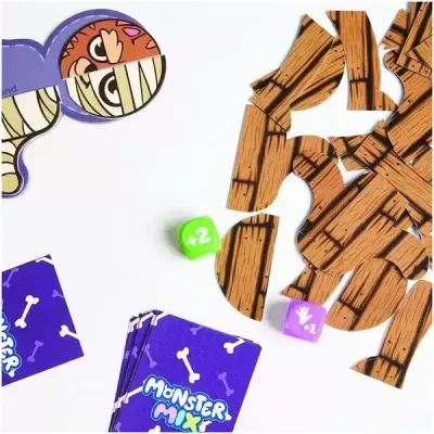 Peças de madeira de jogo, dados coloridos e cartas Monster Mix num fundo branco