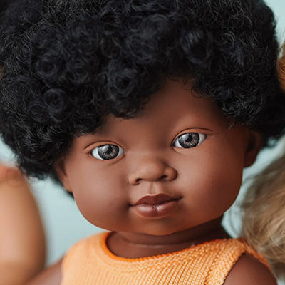 Boneca de pele castanha com cabelo encaracolado e roupa laranja