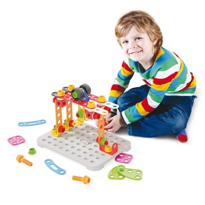 Criança com camisa de riscas coloridas a brincar com brinquedo de construção plástico colorido numa base branca