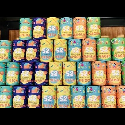 Caixas e latas coloridas com rótulos 52 SEMANAS, 52 AMIGOS, 52 FAMÍLIA e 52 VIAGEM em prateleiras