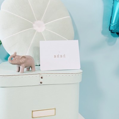 Caixa de armazenamento azul clara com almofada branca e cartão BÉBÉ com elefante decorativo