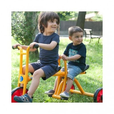 Crianças em triciclo amarelo de três rodas no parque