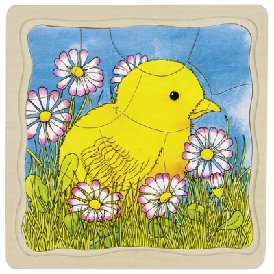 Puzzle de madeira com imagem de pintainho amarelo entre flores no campo