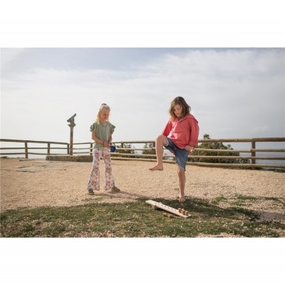 Duas crianças a jogar ao ar livre com tacos de madeira junto a uma cerca de madeira