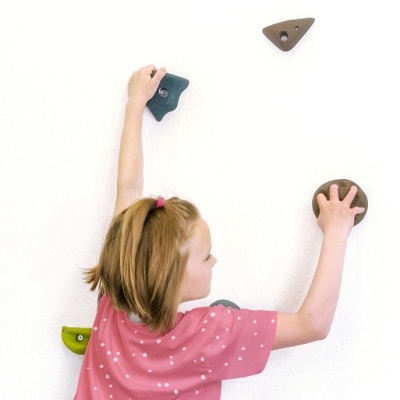 Criança a escalar parede com presilhas coloridas vestindo t-shirt rosa