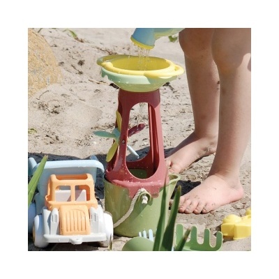 Brinquedo de areia colorido e pés de criança na praia