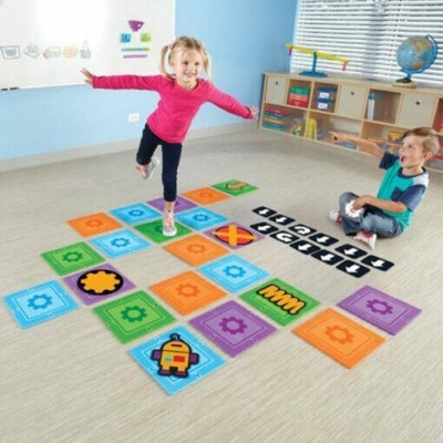 Crianças brincando com tapetes coloridos em sala com mobília clara e globo