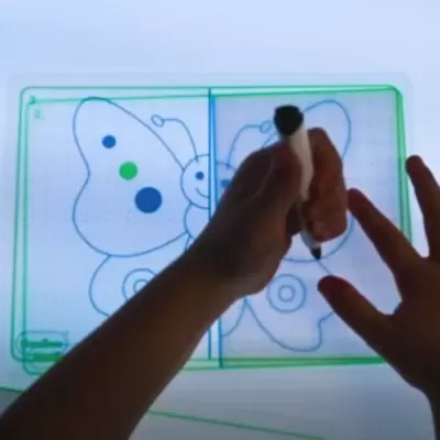 Duas mãos seguram caneta sobre placa transparente com desenho de borboleta colorido