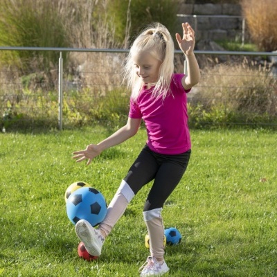 Criança a jogar com bola azul num campo de relva verde
