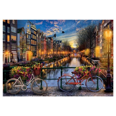 Canal noturno com edifícios panorâmicos e duas bicicletas floridas numa ponte