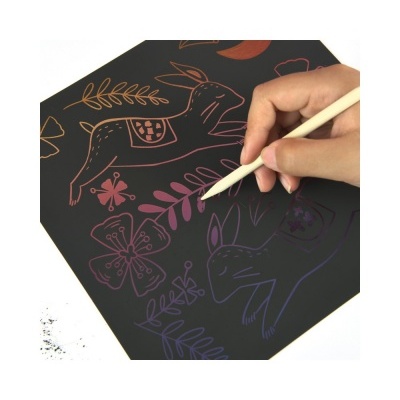 Mão a desenhar em papel preto com caneta branca, desenhos coloridos de coelhos e flores.