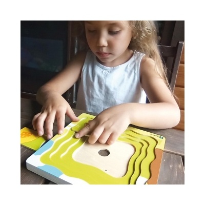 Criança a montar quebra-cabeça de madeira colorido numa mesa