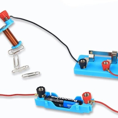 Conjunto experimental com pilha, bobina de cobre, fios com clipes e suporte azul