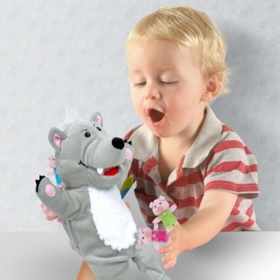 Criança a brincar com fantoches de mão de lobo e porquinhos em tecido cinzento e rosa