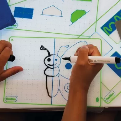 Mãos de criança a desenhar borboleta em base branca com moldes coloridos