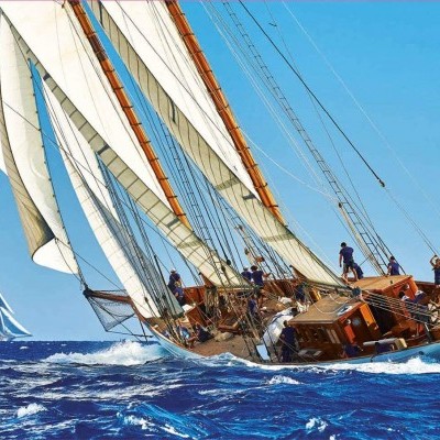 Veleiro clássico com velas brancas a navegar no mar azul