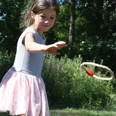 Menina a jogar com anel de corda vermelho em ambiente exterior