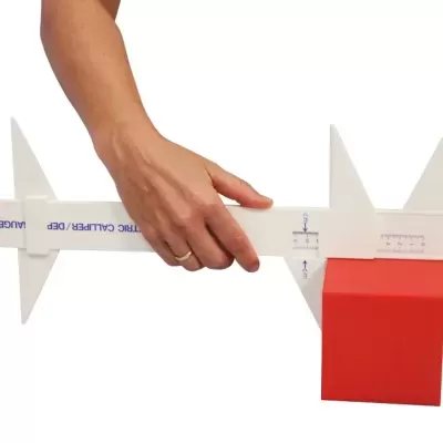 Calibrador branco medindo cubo vermelho