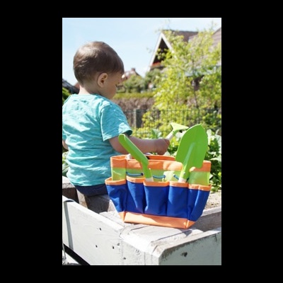 Criança e saco de jardinagem com ferramentas coloridas ao ar livre