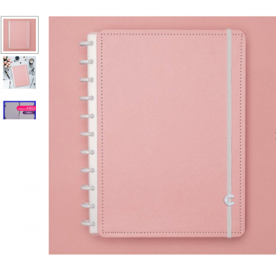 Caderno rosa com elástico cinzento e argolas brancas numa superfície rosa.