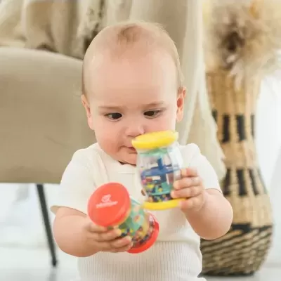 Bebé segurando brinquedos plásticos coloridos no interior