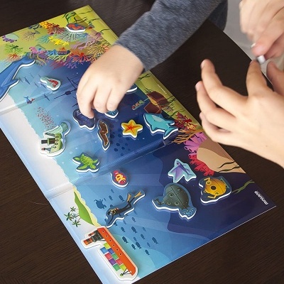 Puzzle infantil marinho com peças de madeira coloridas e crianças a montar numa mesa escura