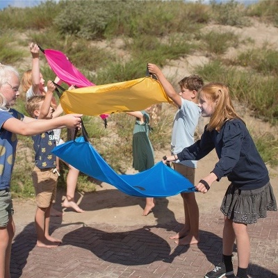 Crianças brincando com panos elásticos coloridos ao ar livre