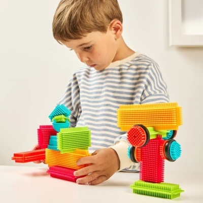 Criança a brincar com blocos de construção coloridos texturizados numa mesa