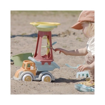 Criança a brincar com carrinho de areia colorido e boné rosa