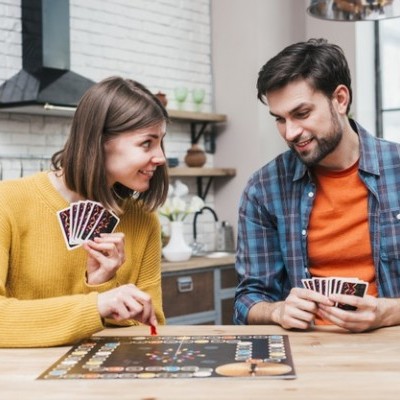 Dois adultos a jogar jogo de tabuleiro numa cozinha moderna com cartas