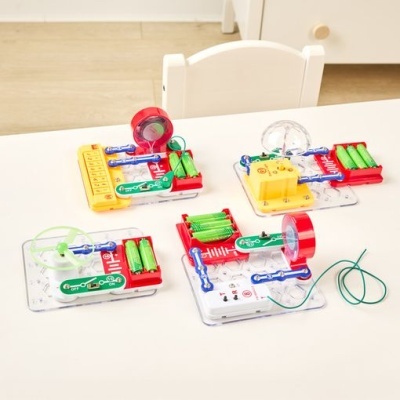 kits educativos de circuitos eletrônicos com componentes coloridos sobre mesa branca