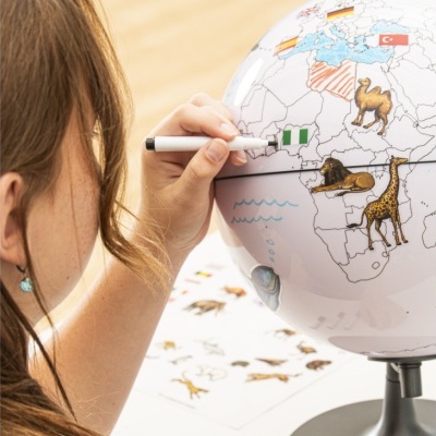 Globo terrestre educativo com desenhos de animais e bandeiras, pessoa a desenhar uma bandeira na superfície.